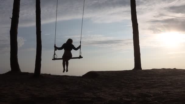 Menina está montando um balanço sobre as falésias sobre o rio — Vídeo de Stock