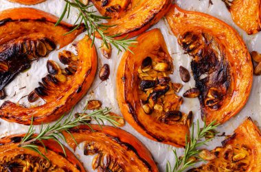 Tohumlu fırında balkabağı dilimleri ve kağıt üzerinde biberiye. Seçici odak.