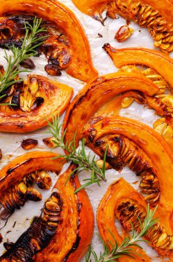 Tohumlu fırında balkabağı dilimleri ve kağıt üzerinde biberiye. Seçici odak.