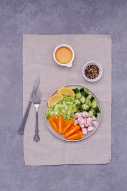 Gri taşlı arka planda sebze dilimlerini bir tabakta karıştır. Seçici odak.