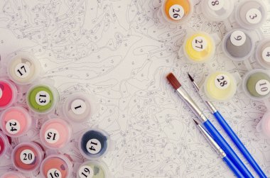 Sayılarla boyamak. Resmi boyamak için ayarlanmış, bir tuval, farklı renkte boyalar, fırçalar. Üst görünüm.