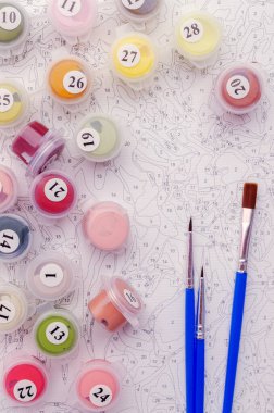 Sayılarla boyamak. Resmi boyamak için ayarlanmış, bir tuval, farklı renkte boyalar, fırçalar. Üst görünüm.