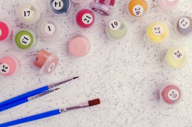 Sayılarla boyamak. Resmi boyamak için ayarlanmış, bir tuval, farklı renkte boyalar, fırçalar. Üst görünüm.