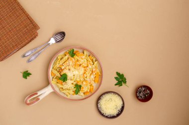 Beyaz soslu balkabaklı makarna seramik bir kapta, arka planda. Seçici odak.