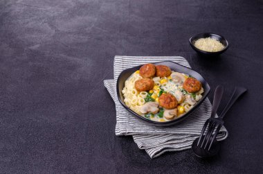 Sebzeli makarna ve siyah arka planda beyaz soslu köfte. Seçici odak.