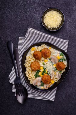 Sebzeli makarna ve siyah arka planda beyaz soslu köfte. Seçici odak.