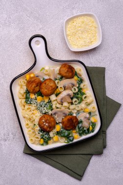 Sebzeli makarna ve gri arka planda beyaz soslu köfte. Seçici odak.