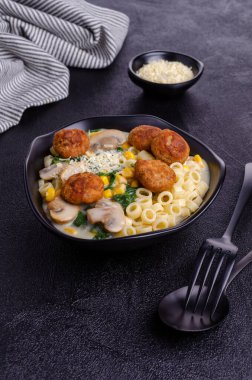 Sebzeli makarna ve siyah arka planda beyaz soslu köfte. Seçici odak.