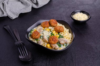 Sebzeli makarna ve siyah arka planda beyaz soslu köfte. Seçici odak.