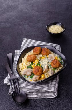 Sebzeli makarna ve siyah arka planda beyaz soslu köfte. Seçici odak.