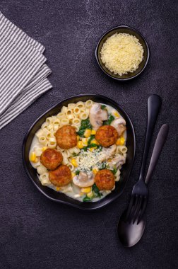 Sebzeli makarna ve siyah arka planda beyaz soslu köfte. Seçici odak.