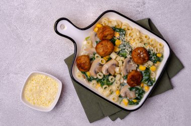 Sebzeli makarna ve gri arka planda beyaz soslu köfte. Seçici odak.