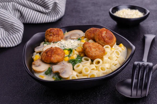 Sebzeli makarna ve siyah arka planda beyaz soslu köfte. Seçici odak.