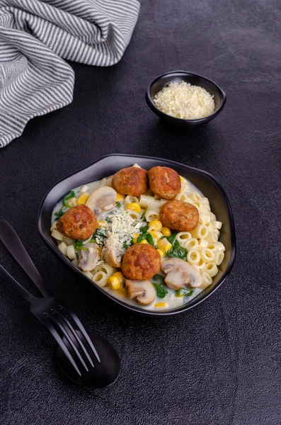 Sebzeli makarna ve siyah arka planda beyaz soslu köfte. Seçici odak.