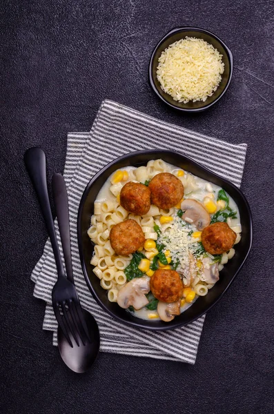 Sebzeli makarna ve siyah arka planda beyaz soslu köfte. Seçici odak.