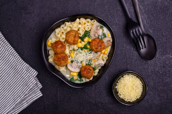 Sebzeli makarna ve siyah arka planda beyaz soslu köfte. Seçici odak.