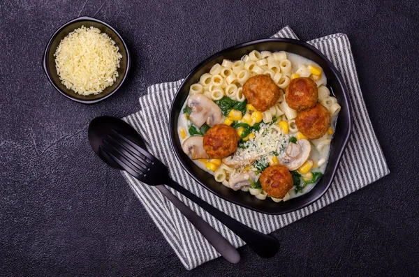Sebzeli makarna ve siyah arka planda beyaz soslu köfte. Seçici odak.