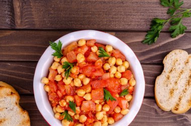 Ahşap arka planda domatesli nohut ve maydanoz. Seçici odak