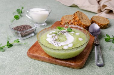 Yeşil arkaplanda yeşil sebzelerden, chia tohumlarından ve bezelye filizlerinden oluşan kalın krema çorbası. Seçici odak.