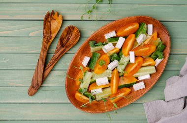 Taze sebze salatası. Salatalık dilimleri, sarı domates, beyaz peynir ve bezelye filizi. Üst Manzara. Yeşil tahta arkaplan.