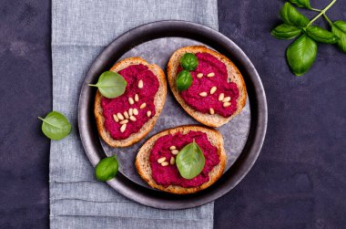 Pancar ezmeli, çam fıstıklı ve fesleğenli üç sandviç. Gri arka plan. Üst Manzara. Seçici odak.