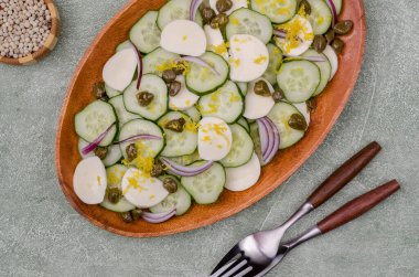 Yeşil arka planda salatalık, peynir, kapari ve limon tatlısı salatası. Üst Manzara. Seçici odak.