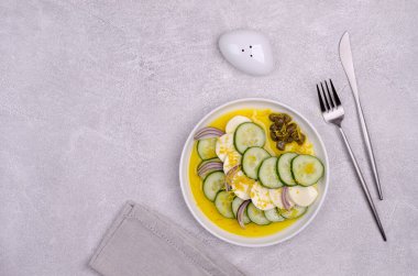 Gri arka planda salatalık, peynir, kapari ve limon tatlısı salatası. Üst Manzara. Seçici odak.