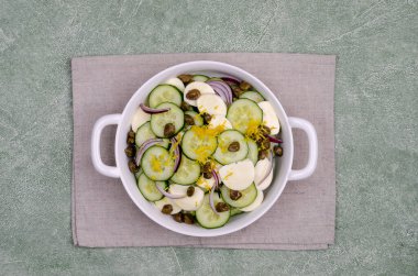 Yeşil arka planda salatalık, peynir, kapari ve limon tatlısı salatası. Üst Manzara. Seçici odak.