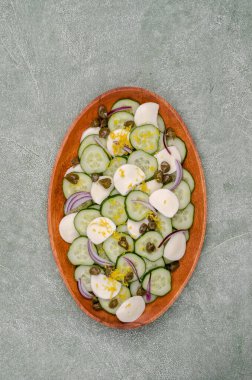 Yeşil arka planda salatalık, peynir, kapari ve limon tatlısı salatası. Üst Manzara. Seçici odak.