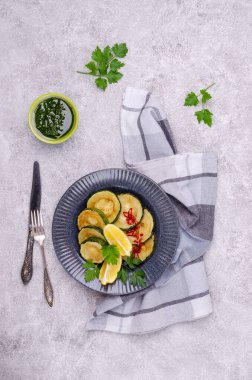 Çimento arka planında yeşil soslu kızarmış kabak. Üst Manzara. Seçici odak.