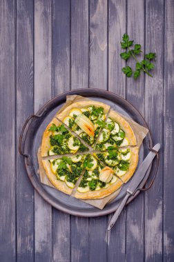 Ahşap arka planda yeşil soslu yuvarlak sebze turtası. Üst Manzara. Seçici odak.