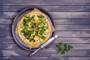 Ahşap arka planda yeşil soslu yuvarlak sebze turtası. Üst Manzara. Seçici odak.