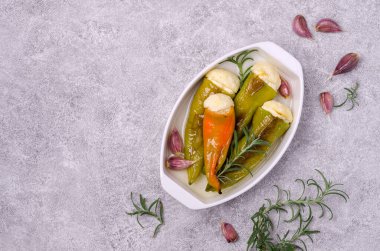 Çimento üzerine sarımsaklı ve biberiyeli ricotta ile doldurulmuş fırında yeşil biber. Üst Manzara. Seçici odak.