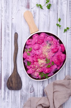 Krema soslu Gnocchi, ahşap arka planda pazı yaprakları ve sapları. Üst görünüm.