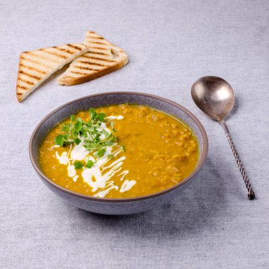 Tekstil arka planında mercimek ve sebzeli kalın çorba. Seçici odak.