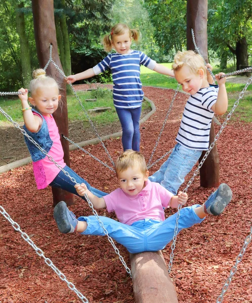 Hilarante niños tener un divertido en un jardín swing . — Foto de Stock