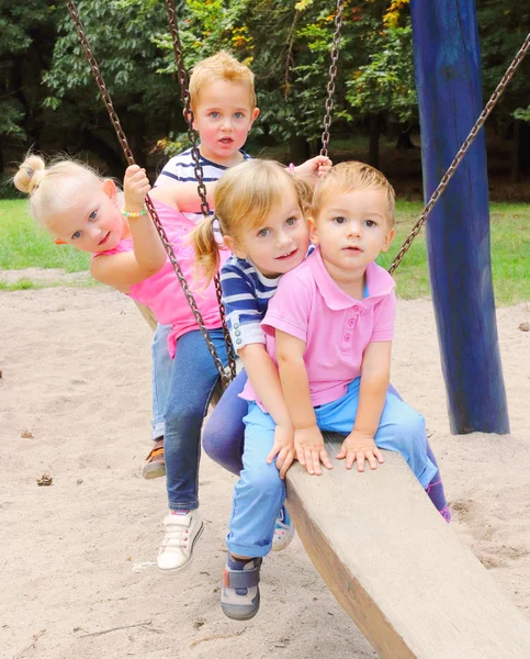 Litle barnen har en rolig på en trädgård gunga. — Stockfoto