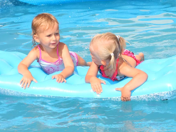 Zwei Kinder schwimmen auf einem aufblasbaren Wasserspielzeug. — Stockfoto