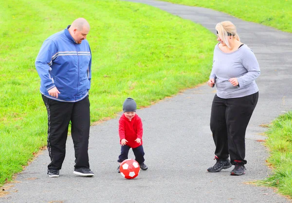 Överviktiga föräldrar med sin son spela fotboll tillsammans. — Stockfoto