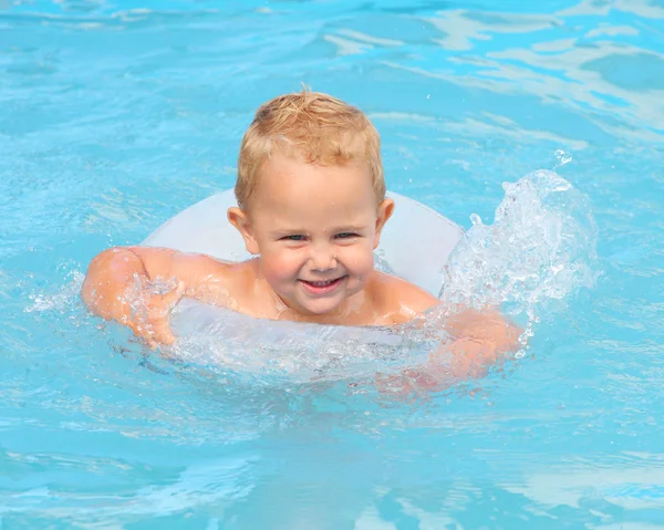 Niño con un anillo de vida disfrutando de la vida en la piscina . Imagen De Stock