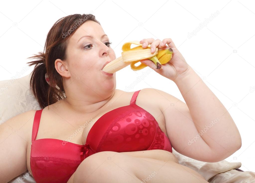 Overweight woman eating sweet banana. 