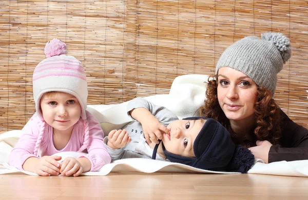 Jonge moeder en haar kinderen gekleed in warme gebreide — Stockfoto