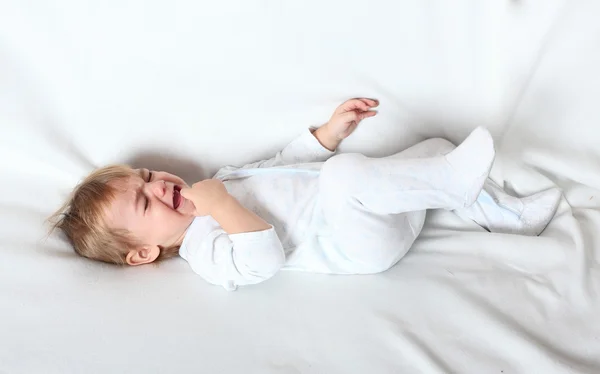 Criança chorando preocupada deitada em uma cama . — Fotografia de Stock