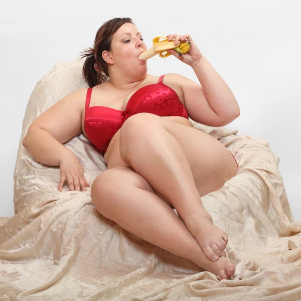 Nadwagę kobieta jedzenie słodki banan. — Zdjęcie stockowe