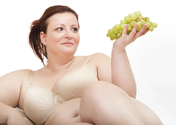 Överviktig kvinna äta grape. — Stockfoto