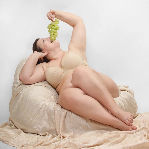 Overweight woman eating grape. — Stock Photo, Image