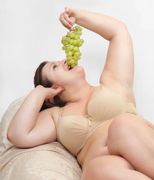 Överviktig kvinna äta grape. — Stockfoto