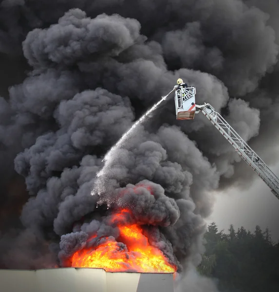 Brandman och brinnande hus. — Stockfoto