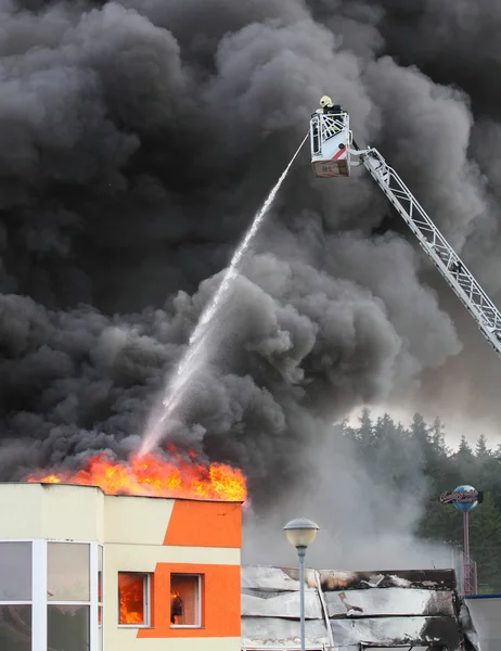 Brandweerman en brandende huis. — Stockfoto