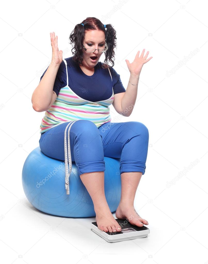 Overweight woman sitting on fitness ball.